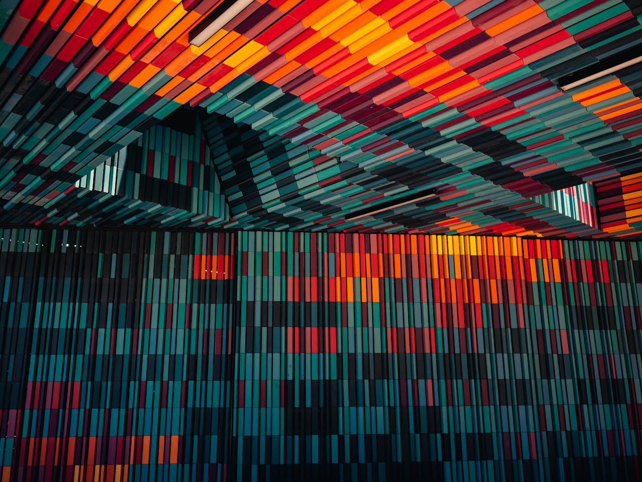 A vibrant, abstract arrangement of colorful geometric patterns on a wall and ceiling indoors.