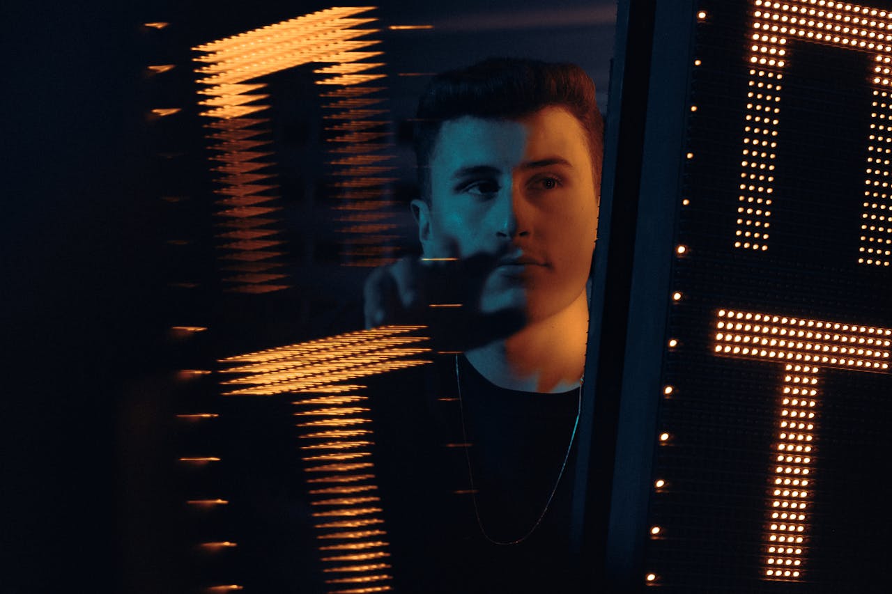 Dramatic portrait of a man reflected with neon lights creating a moody atmosphere.